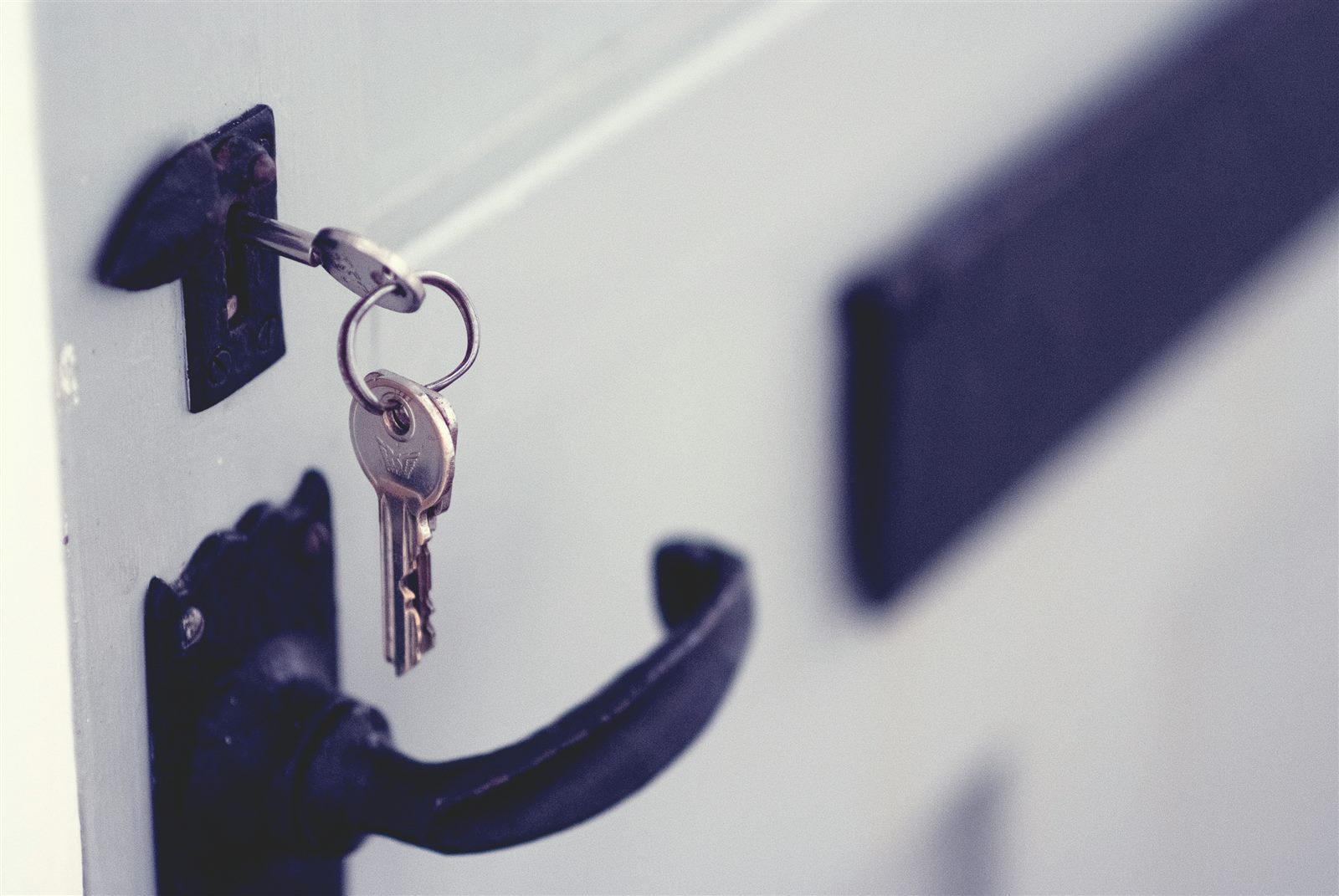 Keys in the lock of a white door with a black handle, the kind of lock change JM All Trades carries out across Ayrshire